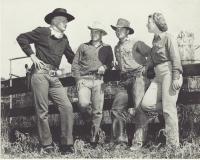 A black and white photo of movie stars dressed up as cowboys