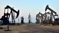 Seven oil and gas pump jacks moving up and down in the San Joaquin Valley, California.