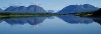 A scenic view of a large lake with mountains and blue sky in the background.