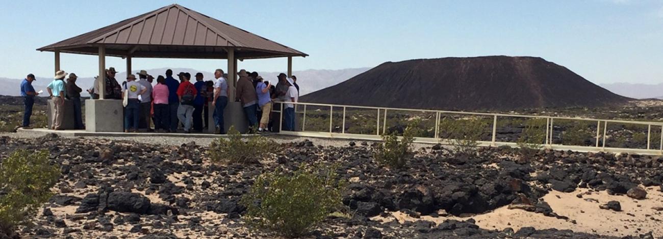 A group of visitors stands beneath a shaded pavilion.