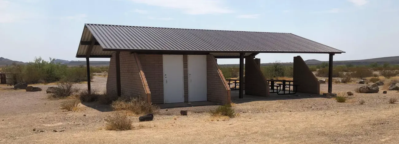A long covered pavilion provides a shaded picnic area in the desert