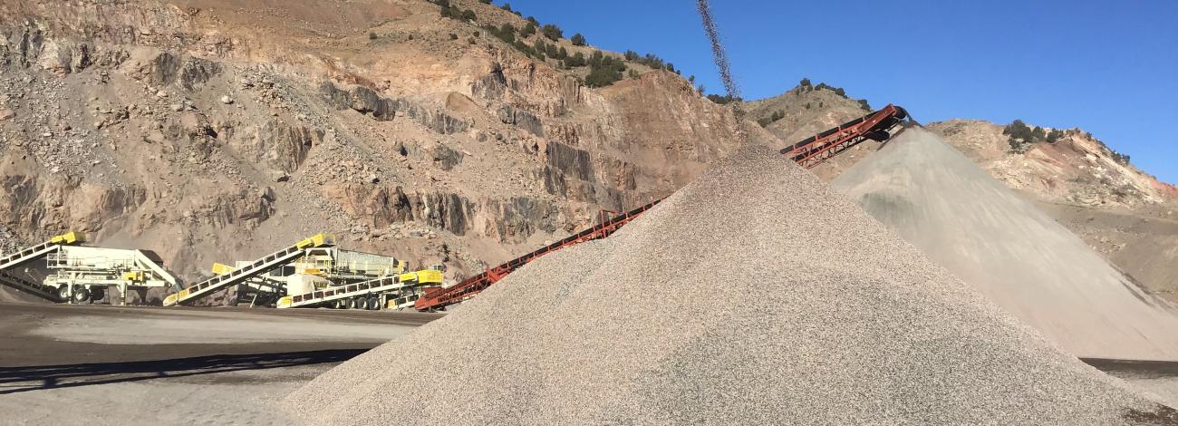Conver belts moving gravel with mining equipment in the background. .