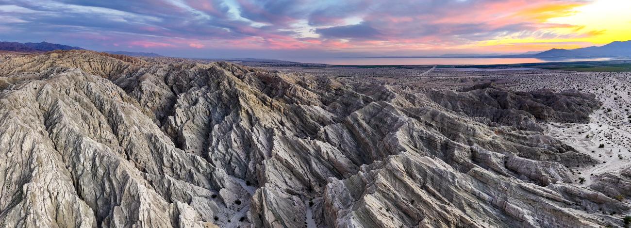 A mountain range of narrow successive ridges under a colorful sunset .