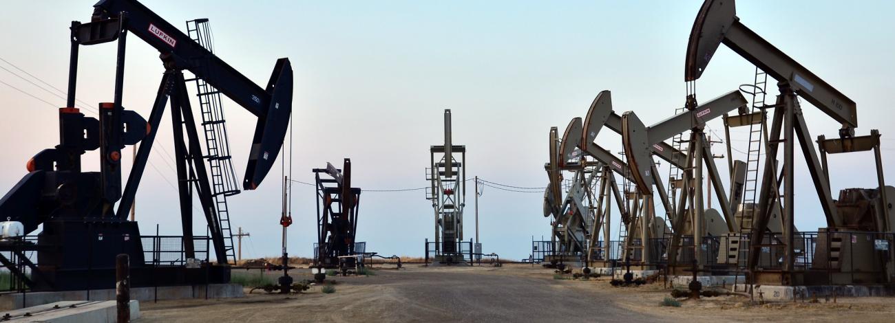 Seven oil and gas pump jacks moving up and down in the San Joaquin Valley, California.