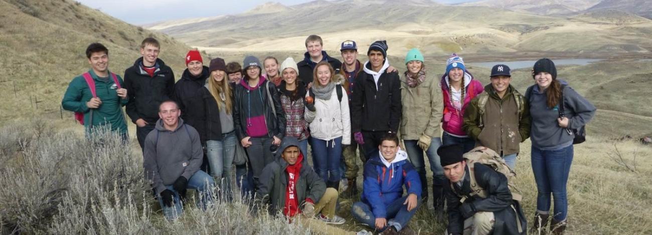 Group of people in field posing. Horizon in background.
