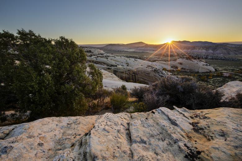 Sun sets over a mountain range in the distance.
