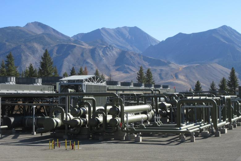 A series of tanks and piped with large mountains in the background.