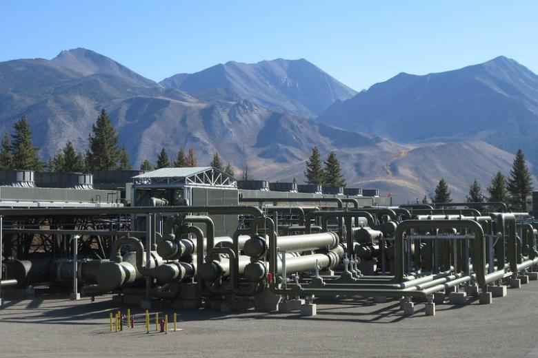A geothermal plant with large mountains in the background.