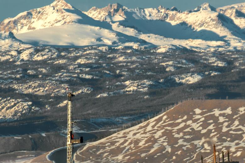 Oil and Gas rig in Wy with snow covered mountains and blue sky