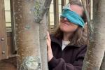 Blindfolded woman smiling at tree.