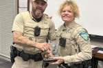 Two police officers with award trophy being held by both.