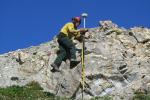 Surveyor on rock face with survey instrument.