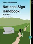 Cover of the Bureau of Land Management’s ‘National Sign Handbook, H‑9130‑1,’ dated September 2016. The illustration shows a trail winding through green hills with two silhouetted hikers and a stone sign structure in the foreground.