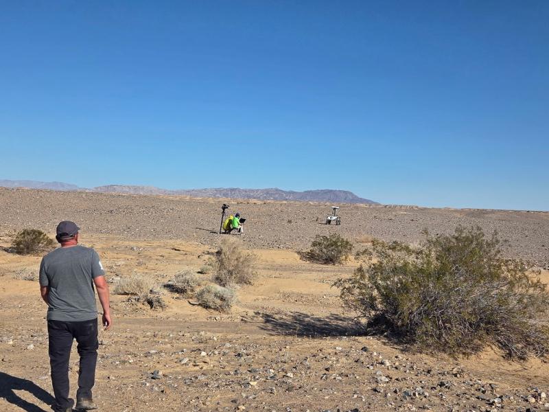 Monitoring the roverin the desert with a man walking
